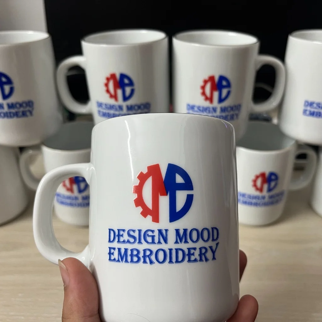 Custom printed ceramic mugs with Design Mood Embroidery gear logo in red and blue